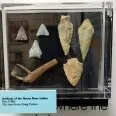 A group of arrow heads and other artifacts in a case